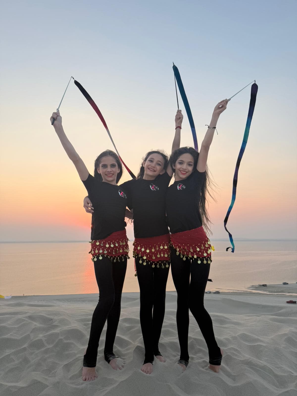 Queens Gymnastics athletes with ribbons at sunset
