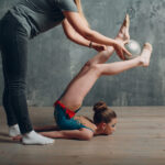 Young girl professional gymnast with coach woman dance rhythmic gymnastics at studio.